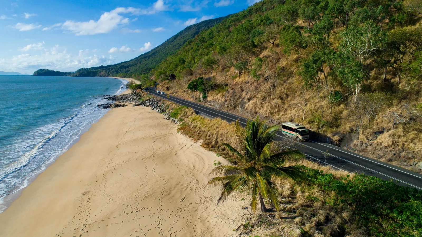 Sandy beach and coast road beside forested hills north of Cairns
