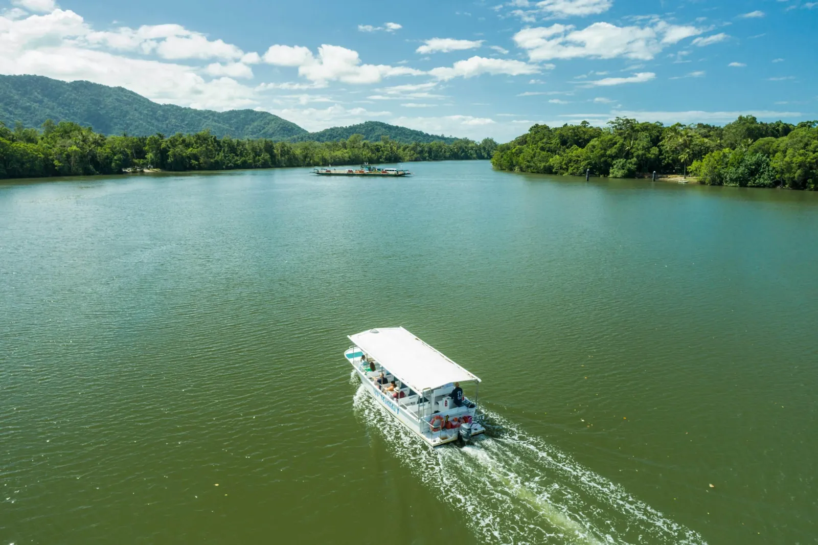 Cruise boat heading down the wide Daintree River toward the ranges