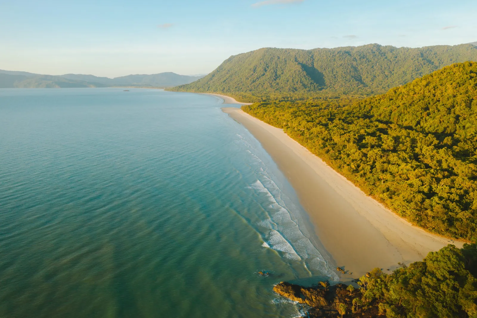Aerial view of a long beach backed by forested ranges on the Daintree coast