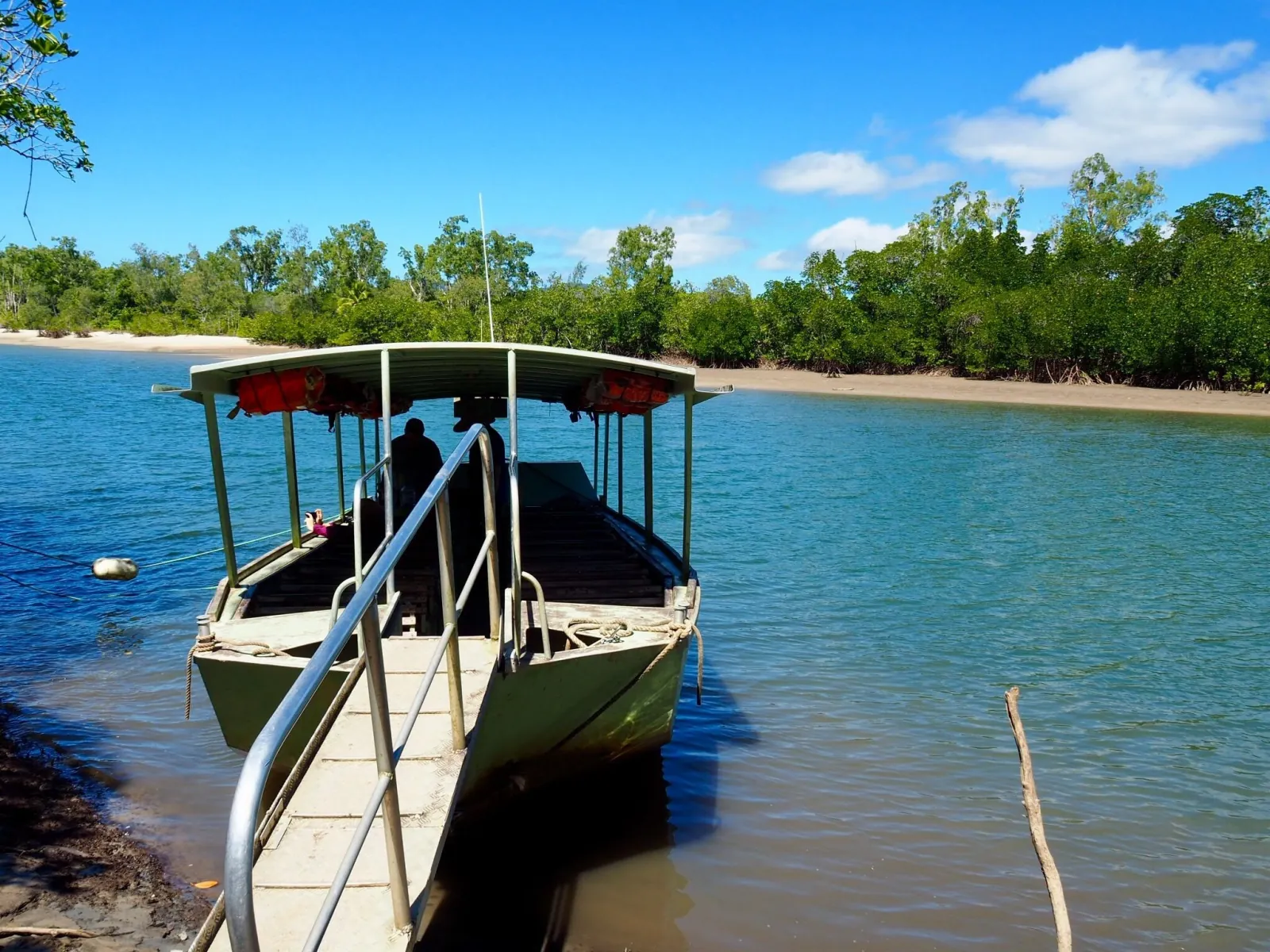 Small cruise boat moored at a jetty on a calm blue river