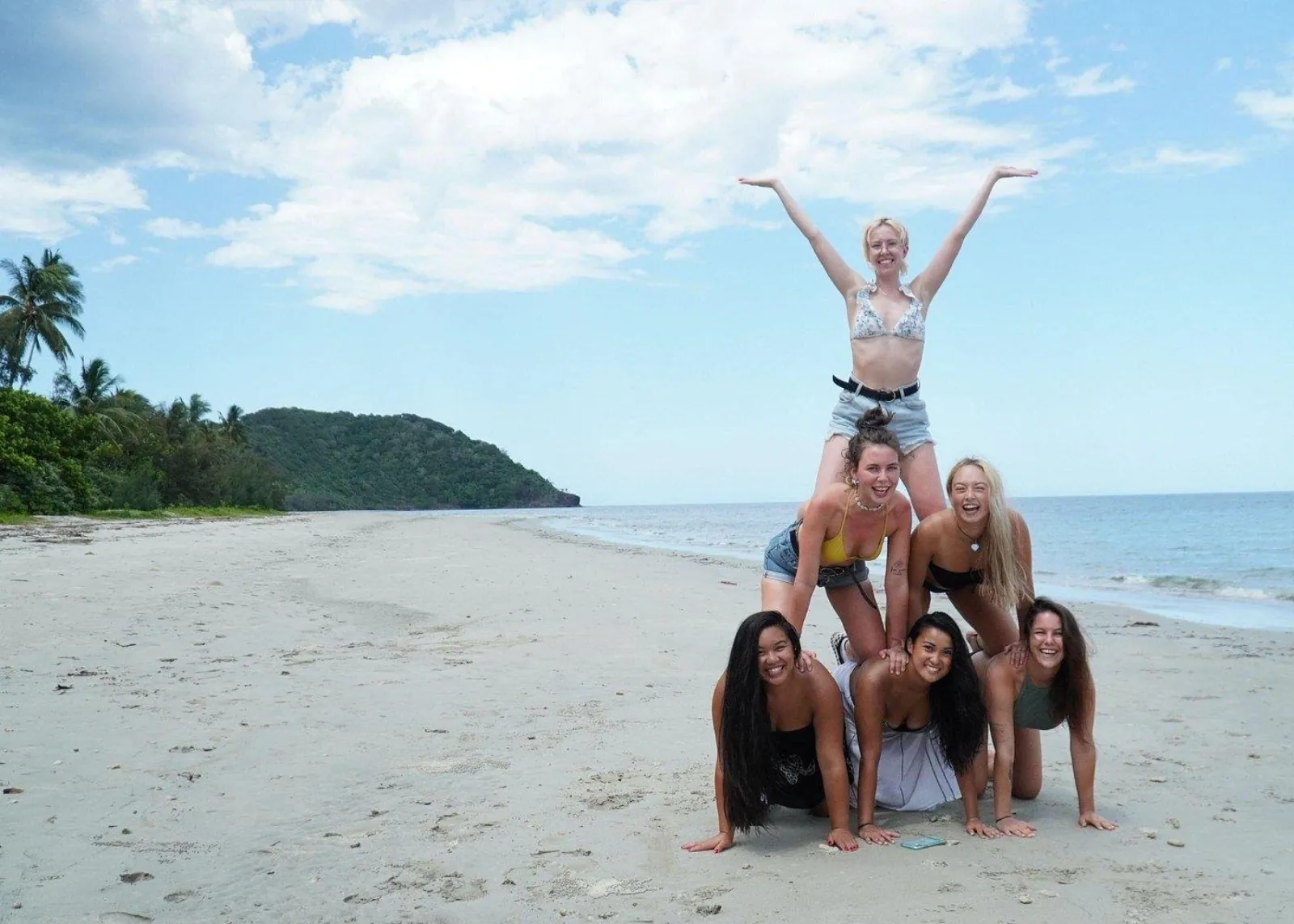Group forming a human pyramid on a Cape Tribulation beach
