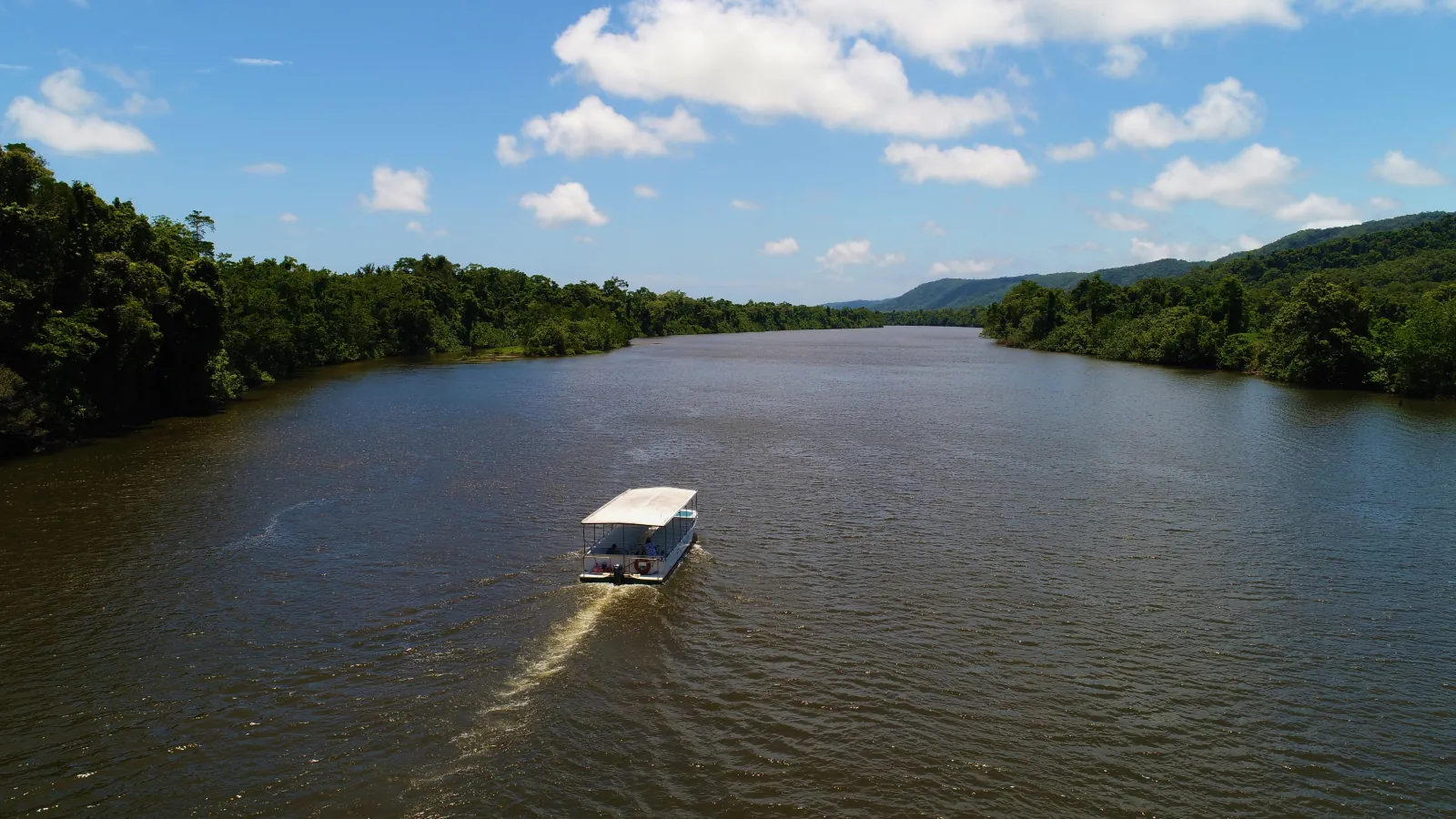 Cruise boat on the Daintree River with the ranges behind