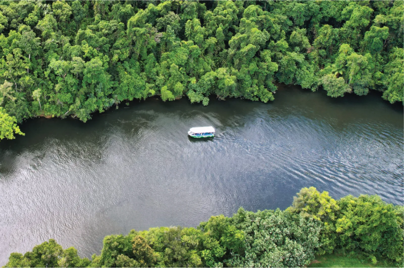 Small boat on a wide bend of the Daintree River from above