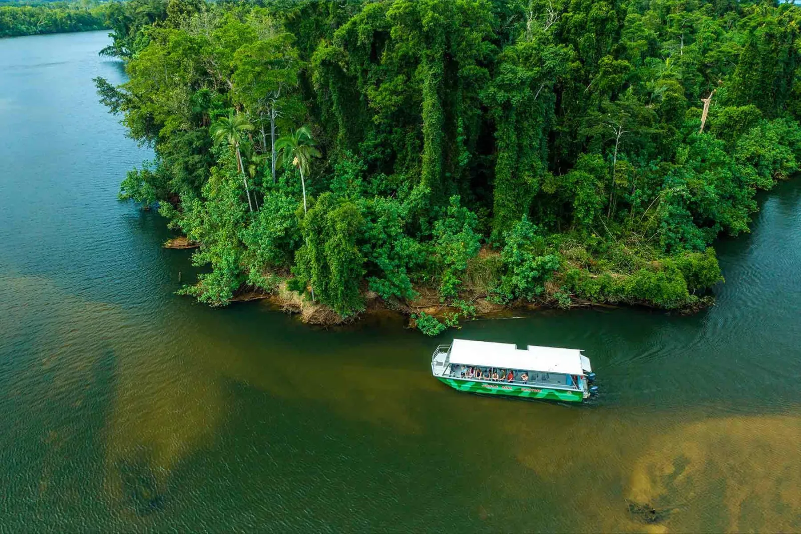 Cruise boat passing a forested island on the Daintree River