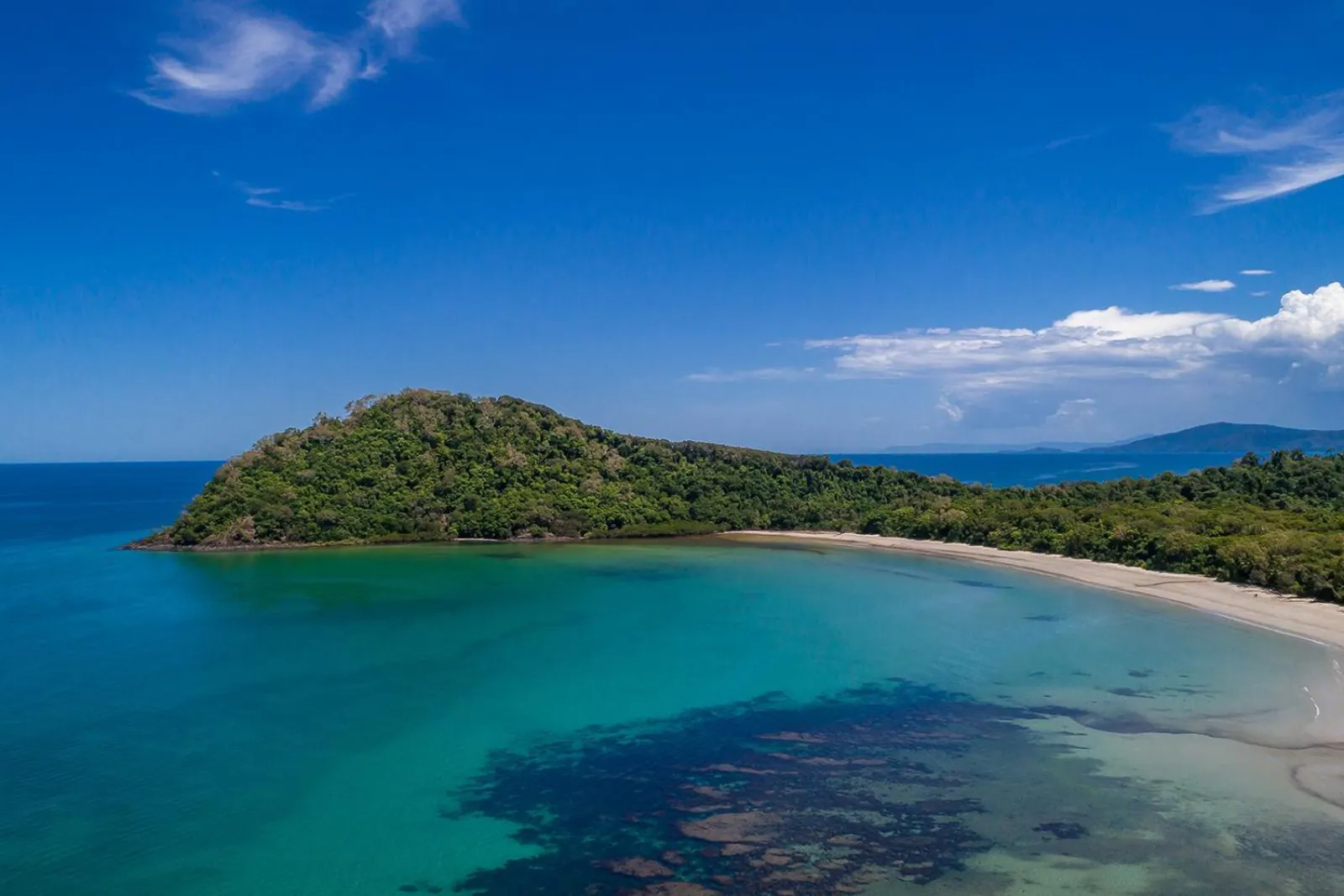 Aerial view of a forested headland and turquoise bay on the Daintree coast